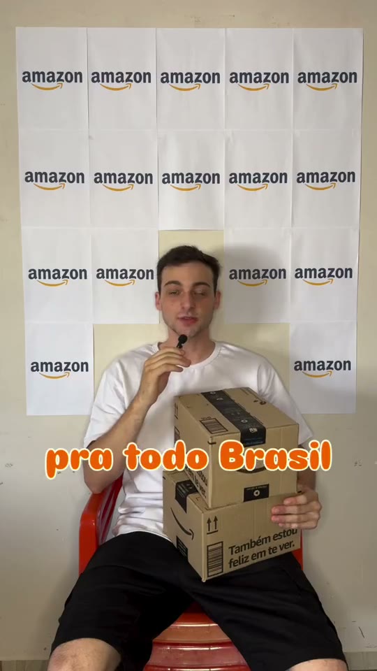 Eduardo segurando caixas da Amazon com o painel da marca ao fundo